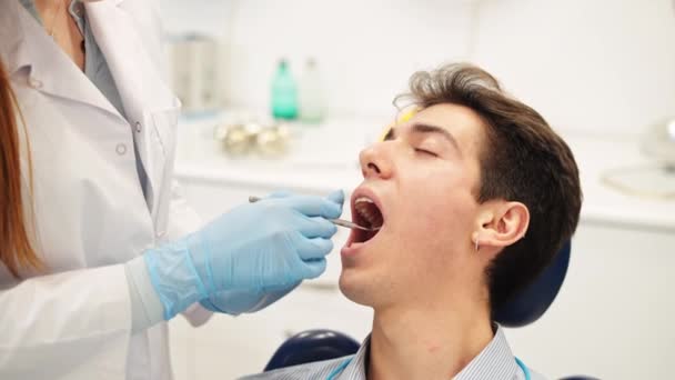 젊은 남성 환자 구강 건강 검진 과 전문적 인 여성 치과 의사의 시각 검진을 받는 모습 — 비디오