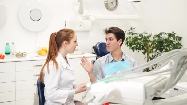 Professional female dentist with digital tablet in hands discussing treatment with male patient — Stock Video