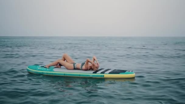 Surfer lying on SUP board in sea — Stock Video