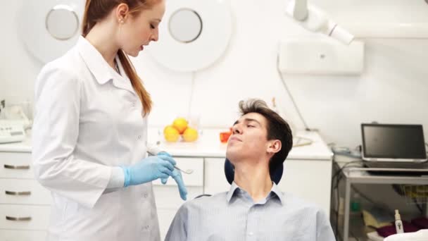 Young attractive female dentist talking with man sitting in dental chair about teeth problems — Stock Video