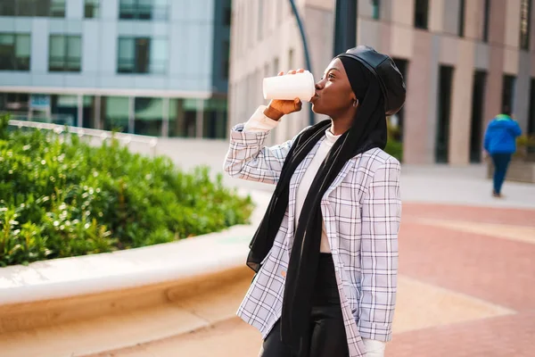 都市公園でイスラムスカーフ飲料コーヒーの黒人女性 — ストック写真
