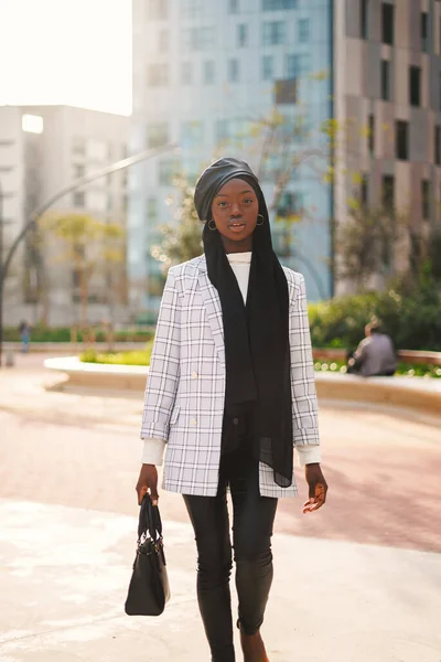 トレンディ黒女性でヘッドスカーフ運ぶバッグで公園 — ストック写真