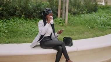 Müslüman kadın kahve içiyor ve sınırda cep telefonu kullanıyor.