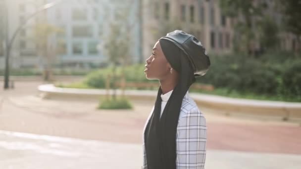 Мусульманка, любующаяся солнечной городской улицей — стоковое видео