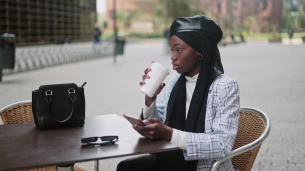 Moslim vrouw met mobiele telefoon in cafetaria straat — Stockvideo