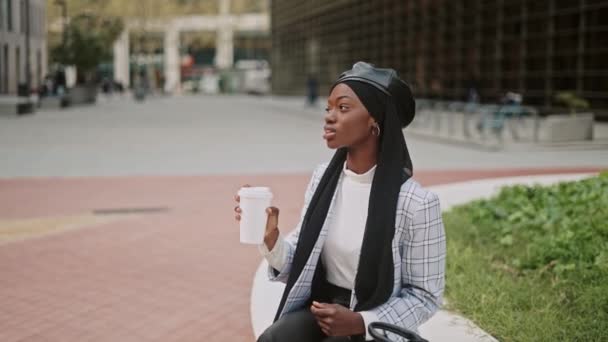 O femeie musulmană bea cafea pe stradă — Videoclip de stoc
