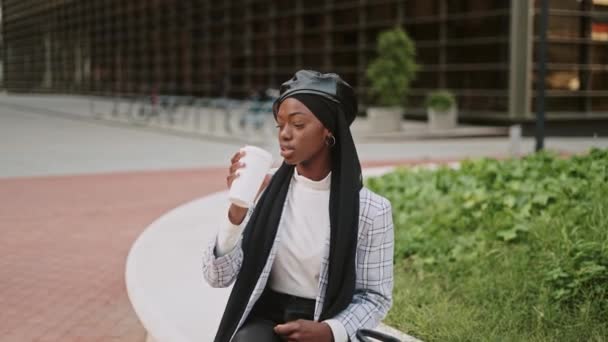 O femeie musulmană bea cafea pe stradă — Videoclip de stoc