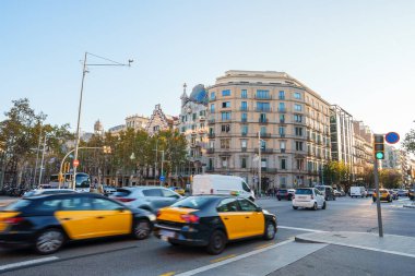 Şehirdeki bulutsuz bir günde tarihi binanın önünde modern taksiler sürüyor.
