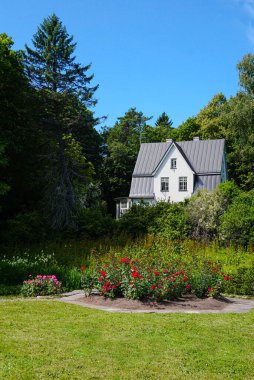 Mükemmel kır evi, sık ağaçlar ve çiçek çalılarıyla çevrili.