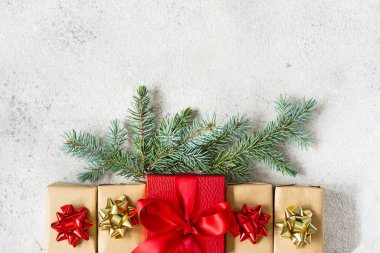 Ortasında büyük kırmızı bir kutu olan birçok küçük hediye kutusu. Gri arka planda köknar dalları olan bayram kağıdına sarılı. Noel ve yeni yıl hediyeleri. Şenlik konsepti, üst görünüm.