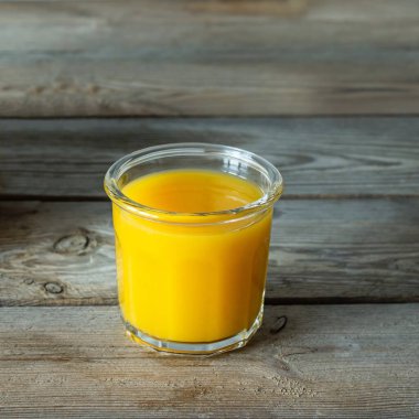Bardakta taze mango suyu ve ahşap arka planda mango dilimi. Egzotik içki, yılın moda renkleri