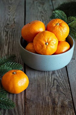 Ahşap zemin üzerinde taze mandalina, meyve ya da turunçgiller bulunan bir kase..