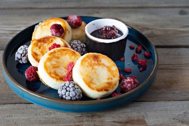 Taze süzme peynir veya taze böğürtlen ve reçelli mavi bir tabakta ricotta krepleri (şurup, börek). Nefis sağlıklı süzme peynirli kahvaltı. Ukrayna mutfağı, Rus mutfağı tatlı yiyecekler
