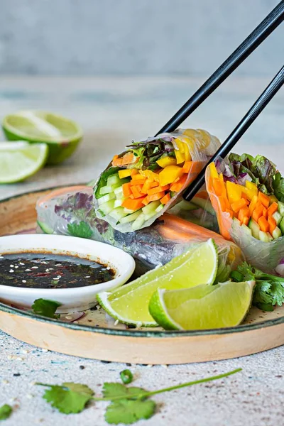 Pirinç kağıdı, çiğ sebze ve açık mavi arka planda acı soslu bitkilerden yapılmış taze Asya aperatifli börekler (Nem). Vietnam Yemekleri