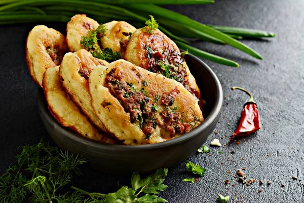 Kıyılmış et parçaları, dereotu, maydanoz ve yeşil soğan, sarımsak, domates sosu ve koyu arkaplanda kırmızı biberli ev yapımı lezzetli krep (börek).. 