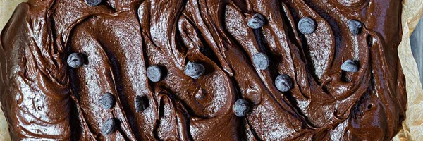 Chocolate texture (mousse) with pieces of chocolate drops. Raw dough for making American brownie dessert, top view.