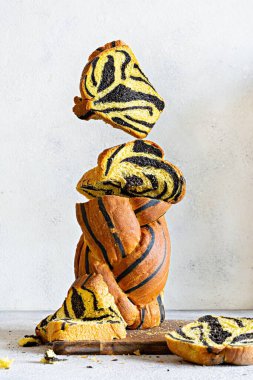 Olağandışı balkabağı mermerli (kaplan desenli) mürekkep balıklı ekmek, açık arkaplanda ahşap bir tahtaya örülmüş. Kullanışlı ev yapımı, havada kalma. Mürekkep balığı mürekkebiyle işlenmiş olağandışı balkabağı mermerli ekmek. Kullanışlı ev yemekleri, havaya yükselme.