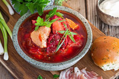 National dish of Ukrainian cuisine borscht with vegetables, turkey meat, herbs, sour cream and traditional bread (bun with garlic and dill, pampushka) with bacon (pork). Cultural heritage.