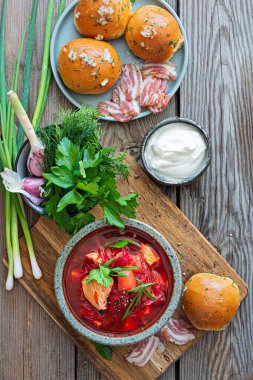 National dish of Ukrainian cuisine borscht with vegetables, turkey meat, herbs, sour cream and traditional bread (bun with garlic and dill, pampushka) with bacon (pork). Cultural heritage.