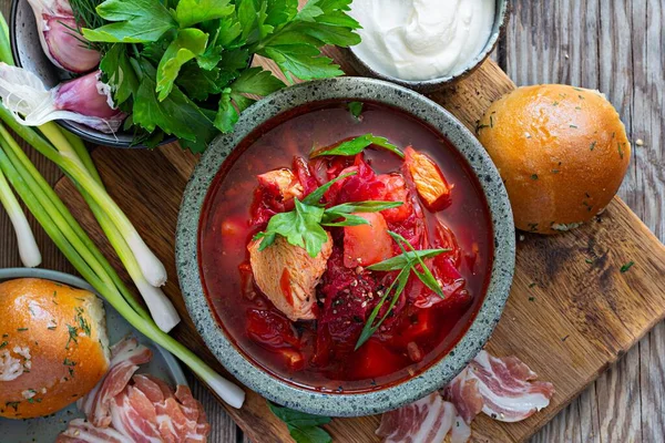 National dish of Ukrainian cuisine borscht with vegetables, turkey meat, herbs, sour cream and traditional bread (bun with garlic and dill, pampushka) with bacon (pork). Cultural heritage.