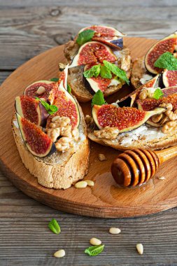 Yumuşak ricotta, olgun incir, ceviz ve çam fıstığı, nane ve bal içeren kızarmış bruschetta (tost)..