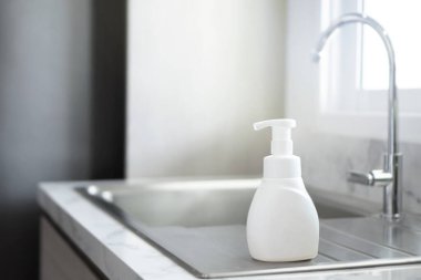 Sabun şişesi tezgahta, banyo arka planında.