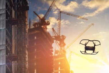 İHA bulutlu gün batımında inşaat alanının üzerinde uçuyor..