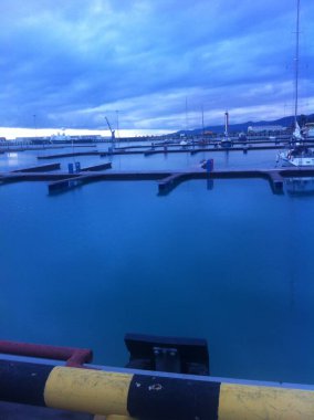 Limanda demirli beyaz karavan yatı. Suyun yüzeyindeki yatın gövdesinin yansıması. Kıç tarafından pruvaya kadar yatın makro görüntüsü. Mavi su, bulutlar. Lüks, lüks, üst sınıf.