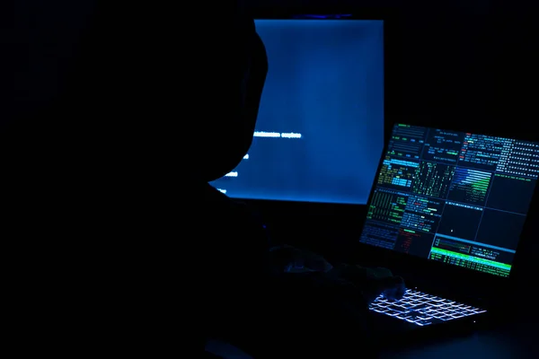 一个计算机程序员和黑客在笔记本电脑键盘上打印代码以闯入一个神秘的组织系统 — 图库照片