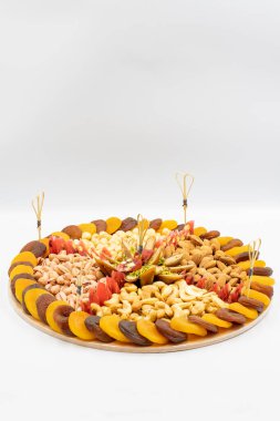 Arka planda karışık fındık tabağı. Fındık, fıstık, kaju, badem ve kurutulmuş kayısıyla hazırlanmış abur cubur tabağı. Dikey görünüm. Kapat.