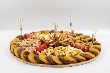 Arka planda karışık fındık tabağı. Fındık, fıstık, kaju, badem ve kurutulmuş kayısıyla hazırlanmış abur cubur tabağı. Yatay görüş. Kapat.