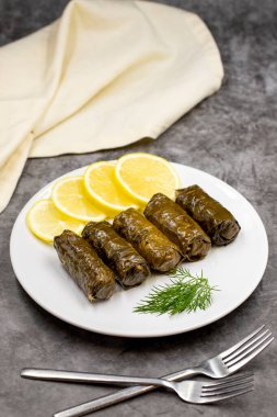 Koyu arkaplanda zeytinyağı ile doldurulmuş üzüm yaprakları. Geleneksel Türk mutfağı lezzetleri. Lezzetli dolma (yaprak sarma). Dikey görünüm. Kapat.