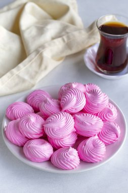 Beyaz tabakta küçük pembe kremalar. Makro atış. Dikey görünüm