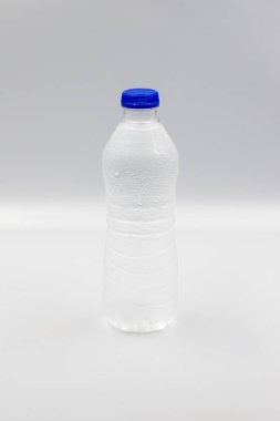 Beyaz arka planda suyla dolu evcil hayvan şişesi. Yakın plan. Dikey görünüm