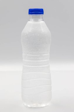 Beyaz arka planda suyla dolu evcil hayvan şişesi. Yakın plan. Dikey görünüm