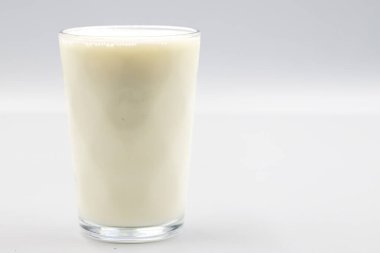 Beyaz arka planda bir bardak inek sütü. Yakın plan. Yatay görünüm