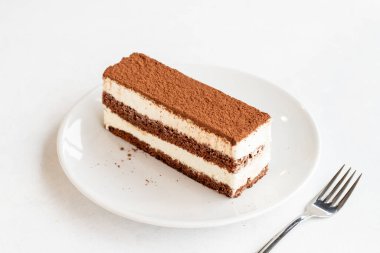 Beyaz arka planda tiramisu tatlısı. İtalyan tatlısı konsepti. Bir tabak tiramisu keki. Kapat. Seçici odaklanma. Yatay görünüm.