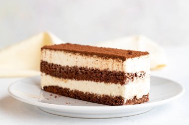 Beyaz arka planda tiramisu tatlısı. İtalyan tatlısı konsepti. Bir tabak tiramisu keki. Kapat. Seçici odaklanma. Yatay görünüm.