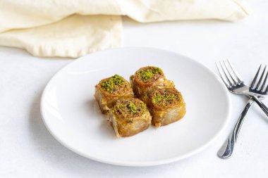 Beyaz arka planda fıstıklı baklava tatlısı. Türk tatlısı konsepti. Bir tabak fıstıklı baklava. Şerbet tatlı Akdeniz fırını. Kapatın. Seçici odaklanma. Dikey görünüm. Hikaye biçimi. Yerel adı fstkl saray sarmas baklava