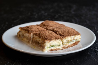 Karanlık bir arka planda soğuk baklava. Türk tatlısı konsepti. Bir tabak dilimlenmiş orman meyveli kek. Bir tabak soğuk süt baklavası. Akdeniz pastanesi. Kapat. Seçici odaklanma. Yatay görüş. Yerel adı soguk baklava
