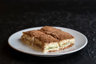 Karanlık bir arka planda soğuk baklava. Türk tatlısı konsepti. Bir tabak dilimlenmiş orman meyveli kek. Bir tabak soğuk süt baklavası. Akdeniz pastanesi. Kapat. Seçici odaklanma. Yatay görüş. Yerel adı soguk baklava