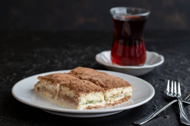 Karanlık bir arka planda soğuk baklava. Türk tatlısı konsepti. Bir tabak dilimlenmiş orman meyveli kek. Bir tabak soğuk süt baklavası. Akdeniz pastanesi. Kapat. Seçici odaklanma. Yatay görüş. Yerel adı soguk baklava