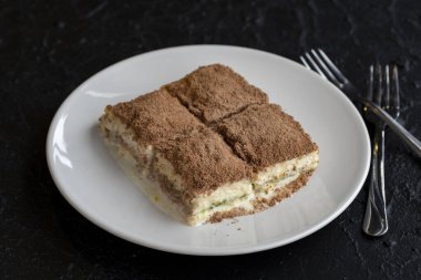 Karanlık bir arka planda soğuk baklava. Türk tatlısı konsepti. Bir tabak dilimlenmiş orman meyveli kek. Bir tabak soğuk süt baklavası. Akdeniz pastanesi. Kapat. Seçici odaklanma. Yatay görüş. Yerel adı soguk baklava