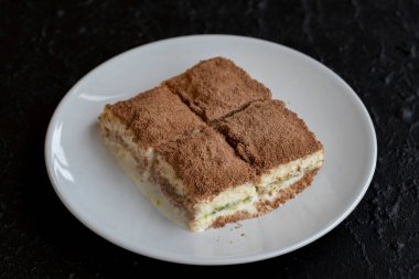 Karanlık bir arka planda soğuk baklava. Türk tatlısı konsepti. Bir tabak dilimlenmiş orman meyveli kek. Bir tabak soğuk süt baklavası. Akdeniz pastanesi. Kapat. Seçici odaklanma. Yatay görüş. Yerel adı soguk baklava
