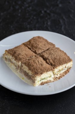 Karanlık bir arka planda soğuk baklava. Türk tatlısı konsepti. Bir tabak dilimlenmiş orman meyveli kek. Bir tabak soğuk süt baklavası..