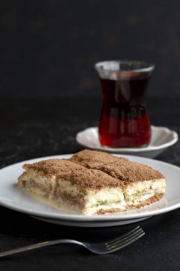 Karanlık bir arka planda soğuk baklava. Türk tatlısı konsepti. Bir tabak dilimlenmiş orman meyveli kek. Bir tabak soğuk süt baklavası..