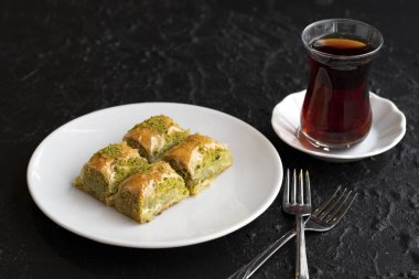 Fıstıklı baklava tatlısı, koyu bir arka planda. Türk tatlısı konsepti. Bir tabak fıstıklı baklava. Şerbet tatlı Akdeniz fırını. Kapat. Seçici odaklanma. Yatay görüş. Yerel adı fistikli baklava