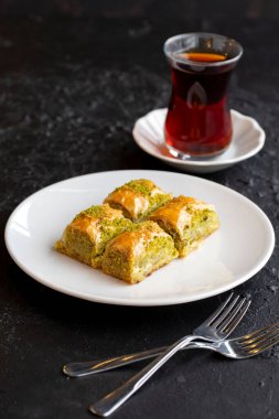 Fıstıklı baklava tatlısı, koyu bir arka planda. Türk tatlısı konsepti. Bir tabak fıstıklı baklava. Şerbet tatlı Akdeniz fırını. Kapat. Seçici odaklanma. Dikey görünüm. Hikaye biçimi. Yerel adı fistikli baklava
