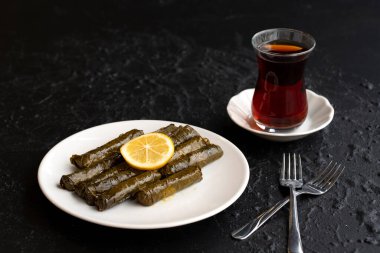 Lezzetli dolma (sarma) doldurulmuş üzüm yaprağı pilav, beyaz yoğurt sosu. Karanlık arka planda doldurulmuş üzüm yaprakları. Lübnan Dolma Sarması tabakta. Lübnan Türkçe Yunanca Ortadoğu mutfağı. 