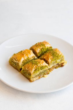 Beyaz arka planda fıstıklı baklava tatlısı. Türk tatlısı konsepti. Bir tabak fıstıklı baklava. Şerbet tatlı Akdeniz fırını. Kapat. Seçici odaklanma. Dikey görünüm. Hikaye biçimi. Yerel adı fistikli baklava